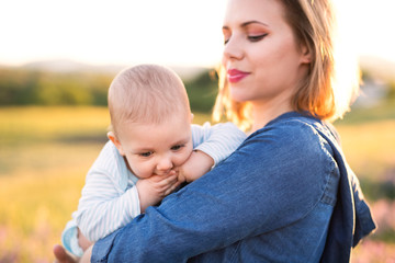 Young mother in nature with baby son in the arms.