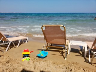 Blick auf Sandstrand mit Sonnenliegen und Kinderspielzeug