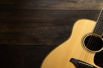 Acoustic guitar resting against a wooden background