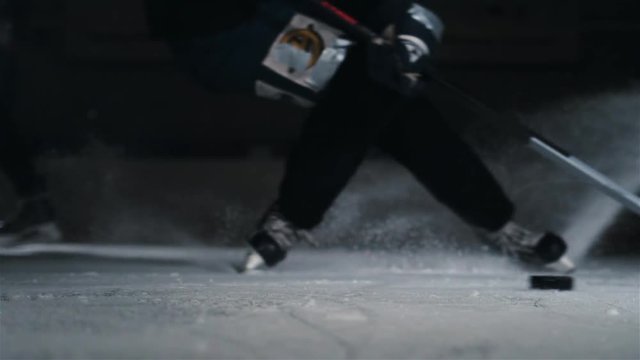 Hockey player make ice sparkles on high speed braking. Motion blur. Legs view only, hockey stick in hands, canadian tricks, stop abrupt deceleration