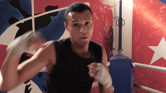 Male boxer doing shadow boxing exercise in a boxing ring. 