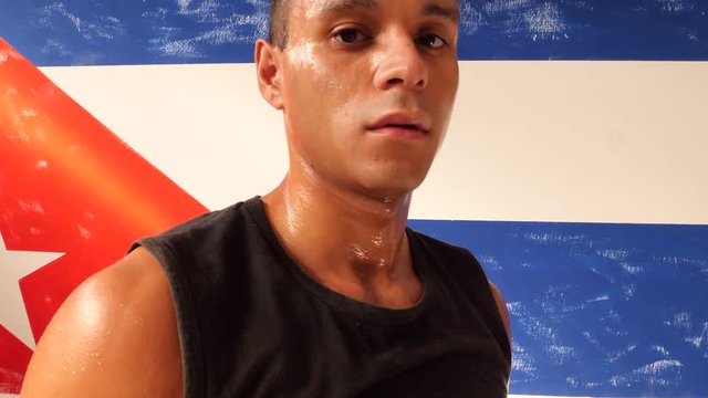 Rise up of sweaty latin american male boxer in a boxing ring looking at camera.