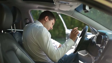 Serious businessman fastening seat belt in car