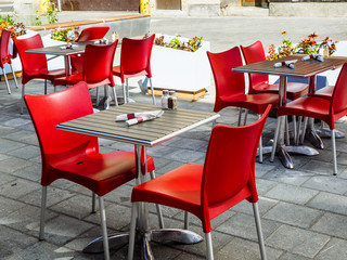 Outdoor patio of a restaurant in urban setting with red chairs