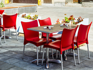 Outdoor patio of a restaurant in urban setting with red chairs