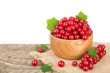 Red currant berries in wooden bowl on wooden table with white background