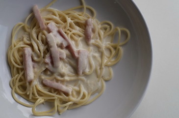 Spaghetti carbonara with ham in white dish served to customers in restaurant for lunch. 