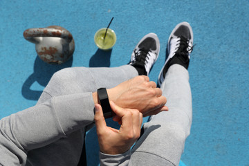 Gym man touching smartwatch screen during workout strength training. Top view from above:...