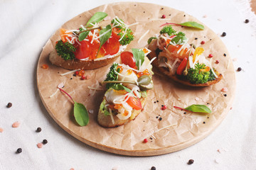 Sandwiches with red fish, tomato, mozzarella and herbs on wooden round board