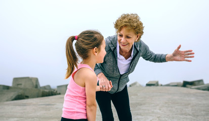 Fototapeta na wymiar Senior sportswoman talking to little girl by pier sea