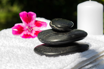 Candles, flowers, stones on a background of greenery for spa massage relaxation