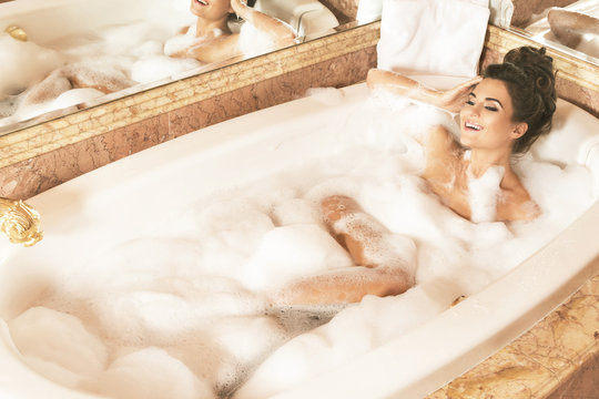Happy and beautiful woman is taking bath with a foam