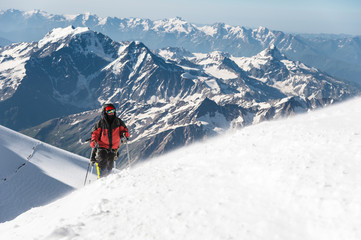 Fototapeta na wymiar The climber climbs the snow-covered summit.