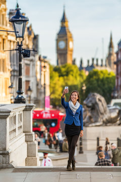 London travel tourist taking selfie picture with mobile phone near Big Ben, UK. Business people at Trafalgar Square, United Kingdom. Europe destination vacation.