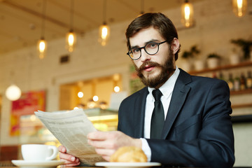 Unemployed man with newspaper reading adverts while hunting for job