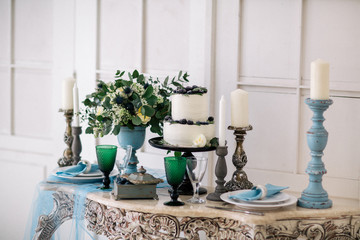 beautiful decorate table with candles, vase with flowers and wedding cake on the table in studio