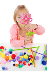 fillette 6 ans jouant avec des pompons de couleurs et des fils chenille