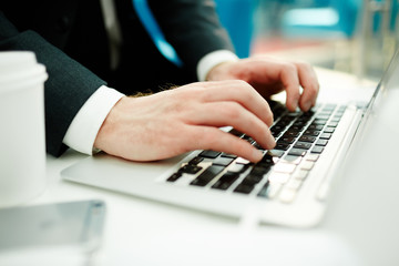 Fototapeta na wymiar Hands of stock trader typing on laptop by workplace