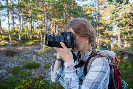 Young woman taking photos in autumn forest with camera