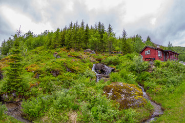House of red boards on a slope near a waterfall