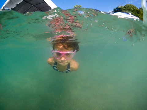 Young Girl Wearing Goggles Swimming Underwater