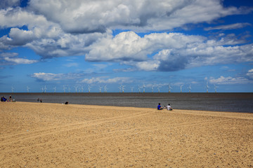 Fototapeta na wymiar A small group of people enjoy a sunny day on a quiet beach in England
