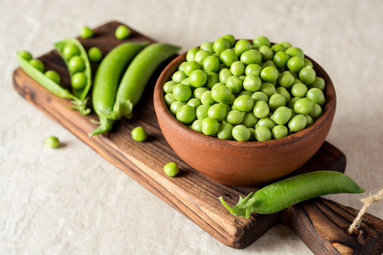 Fresh green peas in ceramic bowl on gray stone background