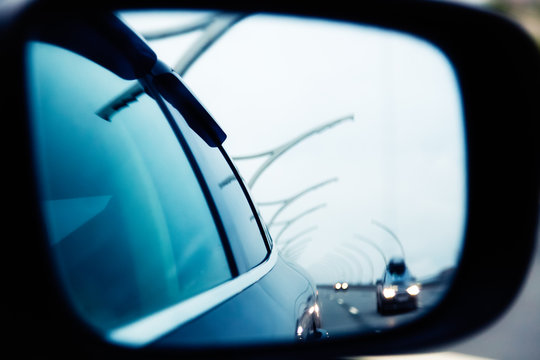 Road reflected in side mirror of car