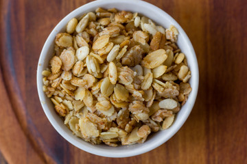 Granola or muesli in white ceramic bowl over wooden table.