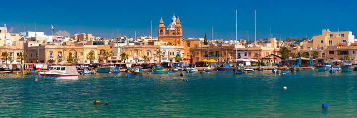 Panorama with traditional eyed colorful boats Luzzu in the Harbor of Mediterranean fishing village Marsaxlokk, Malta - obrazy, fototapety, plakaty