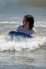 Obraz premium Girl surfing the waves in the ocean on a boogy board
