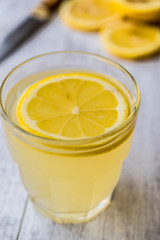 Lemon Liqueur Limoncello with lemon on white wooden surface.
