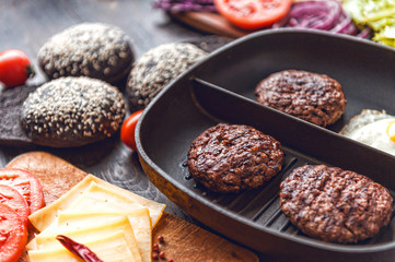 Ingredients for a black burger on a wooden surface