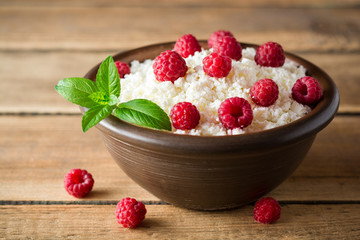 Cottage cheese with raspberry and mint in ceramic bowl on rustic wooden table