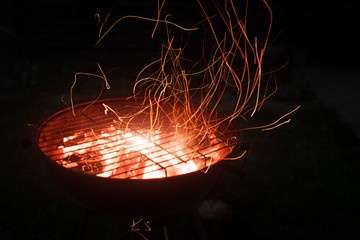Burning coals and sparks coming out of the barbecue. BBQ brazier with sparks.
