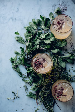Bunches of mint leaves surrounding three cocktail drinks
