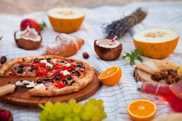 Picnic on the beach at sunset in the white plaid, food and drink conception