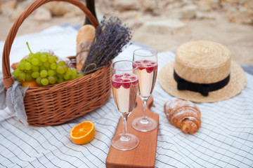 Two glasses of champagne. Picnic on the beach at sunset in the white plaid, food and drink conception