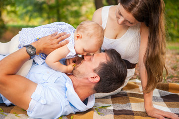 Happy young family spending time outdoor on a summer day, picnic in the park.