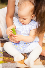 Happy young mother with child spending time outdoor on a summer day, picnic on park.