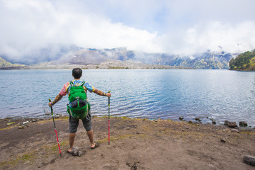 Fototapeta na wymiar Man Traveler with backpack mountaineering Travel Lifestyle concept lake and mountains on background view at Rinjani, Indonesia.