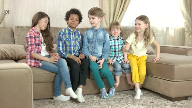 Children playing rock paper scissors. Cheerful kids sitting on sofa. From winning to losing.