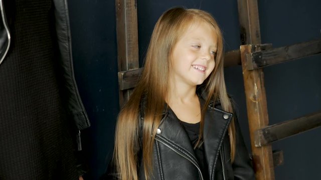 girl with long hair in black leather jacket next to her mother stands in the studio