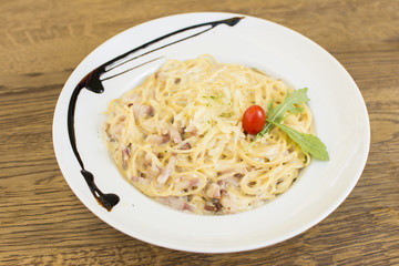 Plate of delicious spaghetti Carbonara with savory minced beef and tomato sauce garnished with parmesan cheese and basil, overhead view.