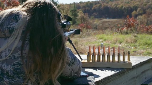 Woman in camo shoots sniper rifle, close up slow motion