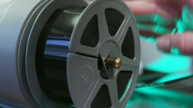 Person places film on spool, close up