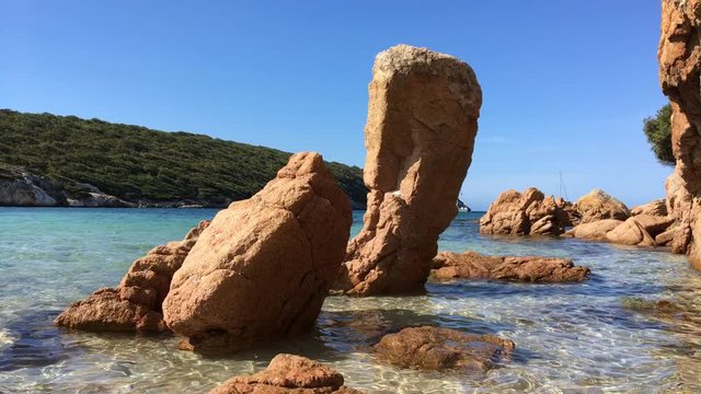 Acqua trasparente nella spiaggia con rocce rosse a picco