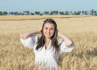 Pretty female smiling in wheat field at warm sunner day