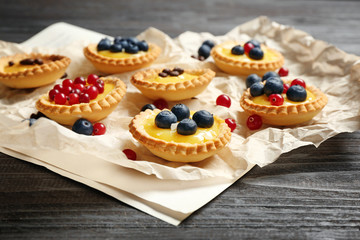 Delicious crispy tarts with berries and custard cream on wooden table