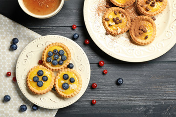 Delicious crispy tarts with custard cream on plates